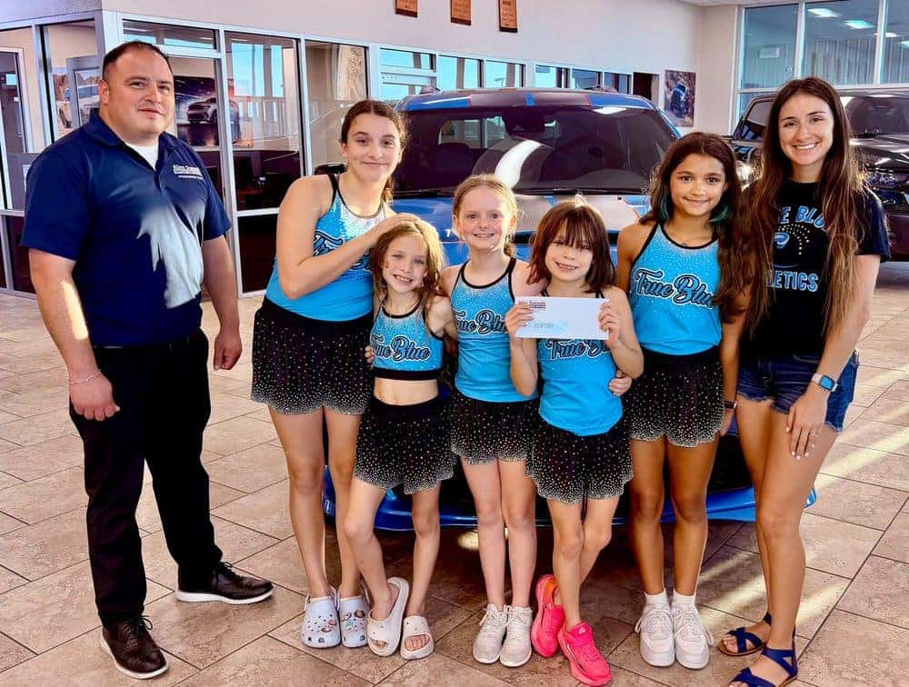 Allen Samuels manager presenting a donation to a local youth cheer team