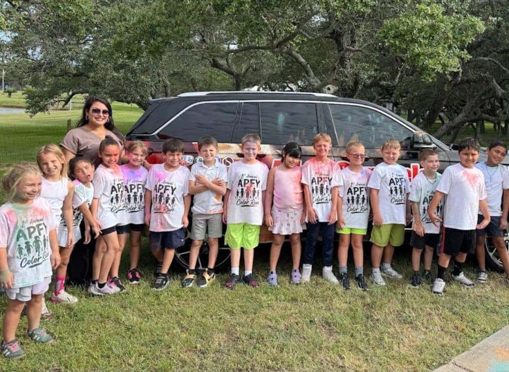 Children at the APFY Color Run in front of an Allen Samuels sponsor vehicle