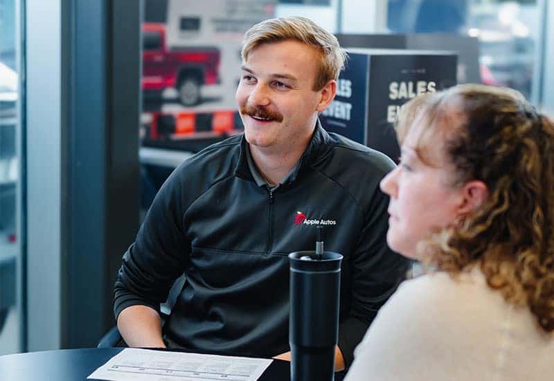 Customer and Salesperson sitting at table looking at something out of frame