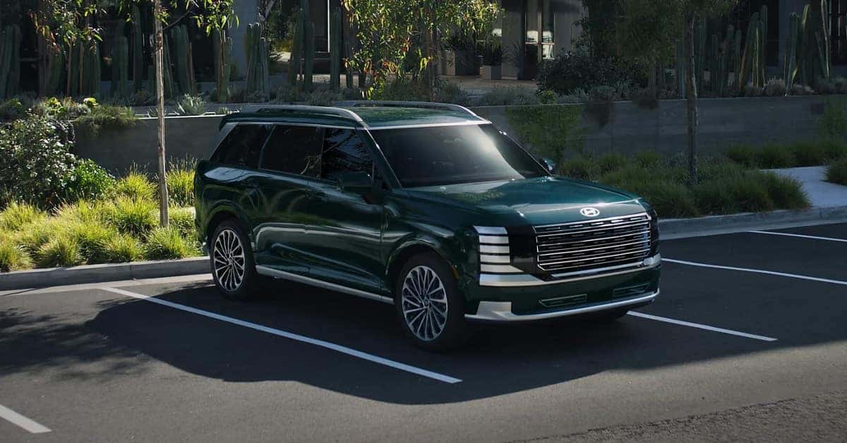 A sleek, dark green SUV is parked in an outdoor.
