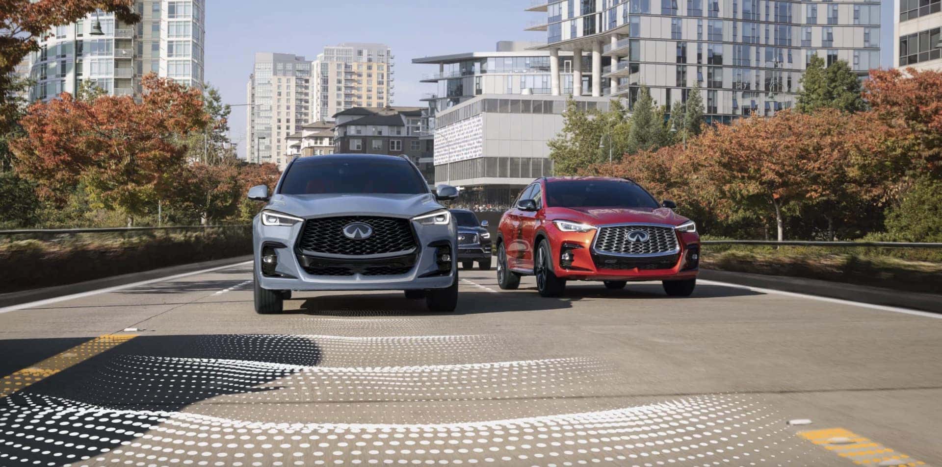 Three 2025 INFINITI QX50 vehicles driving through a city