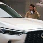 A woman walking by a white 2025 INFINITI QX60