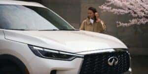 A woman walking by a white 2025 INFINITI QX60