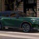A green 2026 INFINITI QX60 driving on the road
