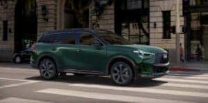 A green 2026 INFINITI QX60 driving on the road