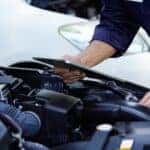 A mechanic in work gloves repairing a car engine in an auto repair shop