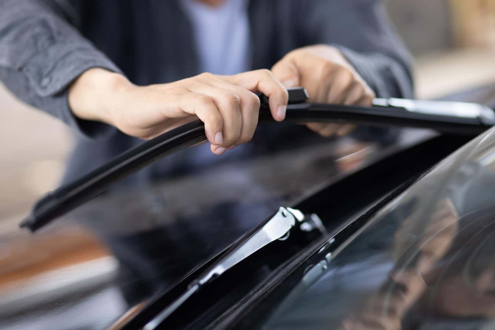 A man replacing windshield wipers on a vehicle