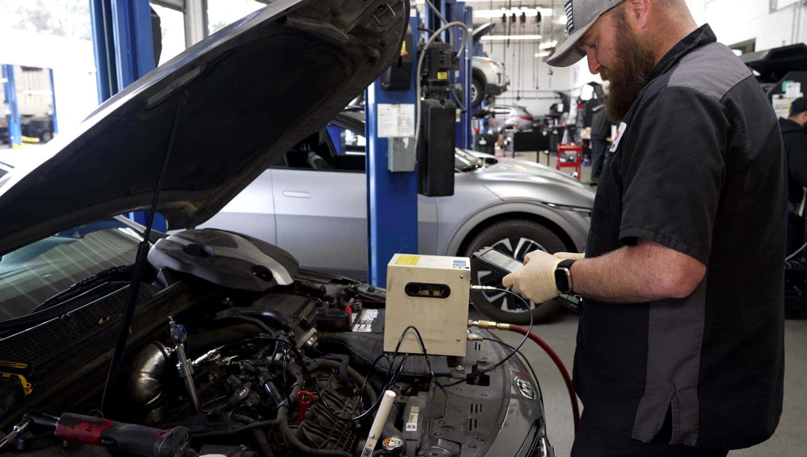 Hello Kia of Valencia Service technician working on a Kia vehicle with the hood raised. 