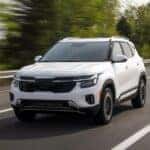 Image of a white 2025 Kia Seltos driving on a paved road