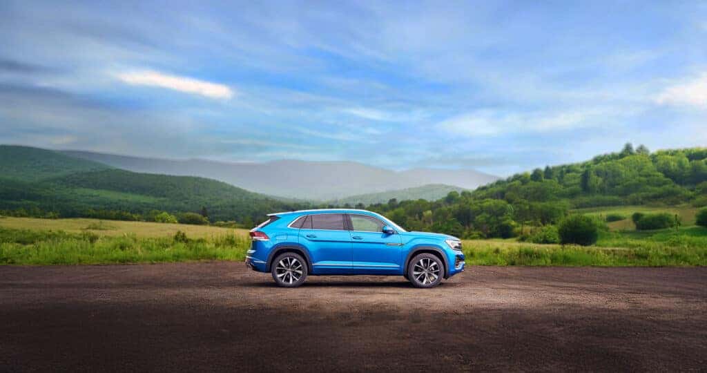 Side view of a 2025 Volkswagen Atlas Cross Sport parked in the country in front of a mountainscape
