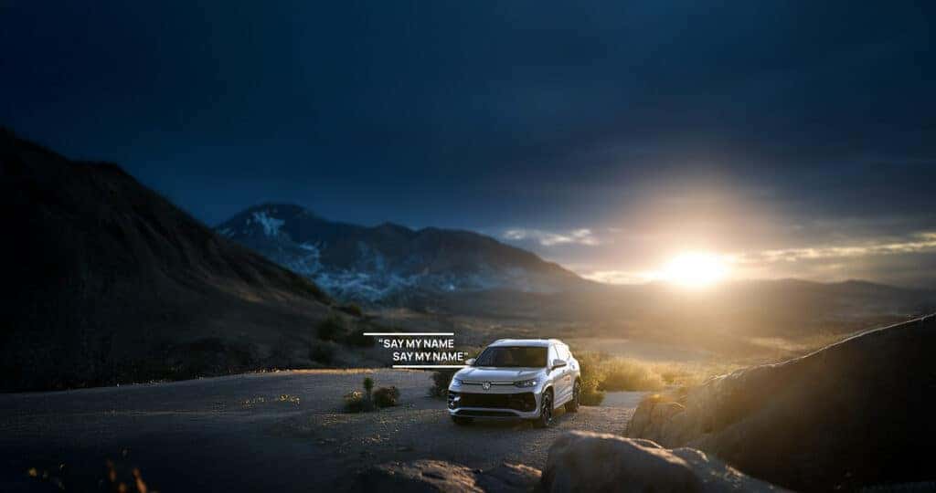 Volkswagen Tiguan pronunciation image of a 2025 Tiguan parked in the desert at sunset with text written on it