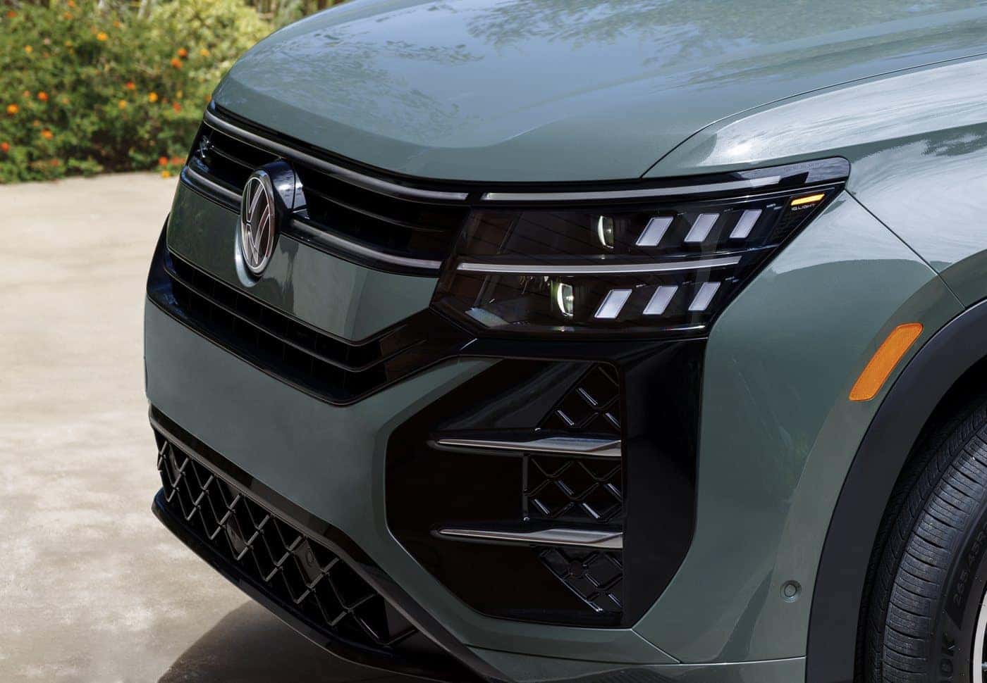 2027 Volkswagen Atlas Cross Sport front with stacked LED headlights and illuminated badge in Dark Sage