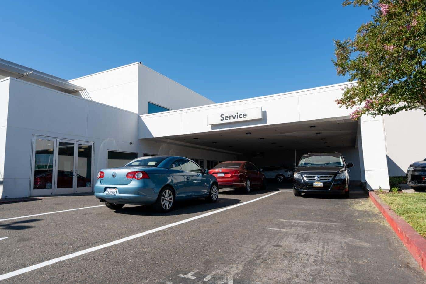 Customer cars pulling into the covered Service drive at Elk Grove Volkswagen on a sunny day