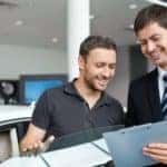 Man buying a car from a salesperson at a dealership