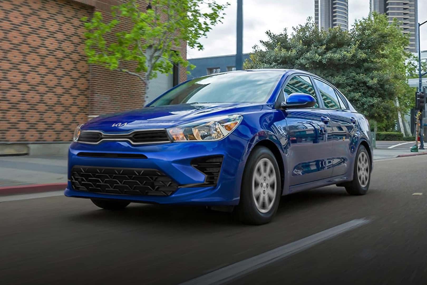 Blue Kia Rio driving in an urban setting