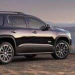 Black 2019 GMC Acadia overlooks wooded mountains and hills at sunset