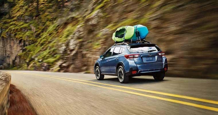 Subaru driving down road with two kayaks