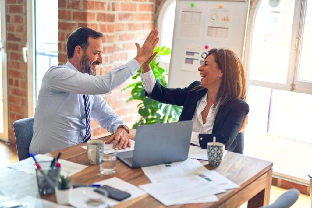 two people high-fiving in an office setting