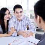 Portrait of happy couple shaking hands with car dealer after buy a new car in the showroom
