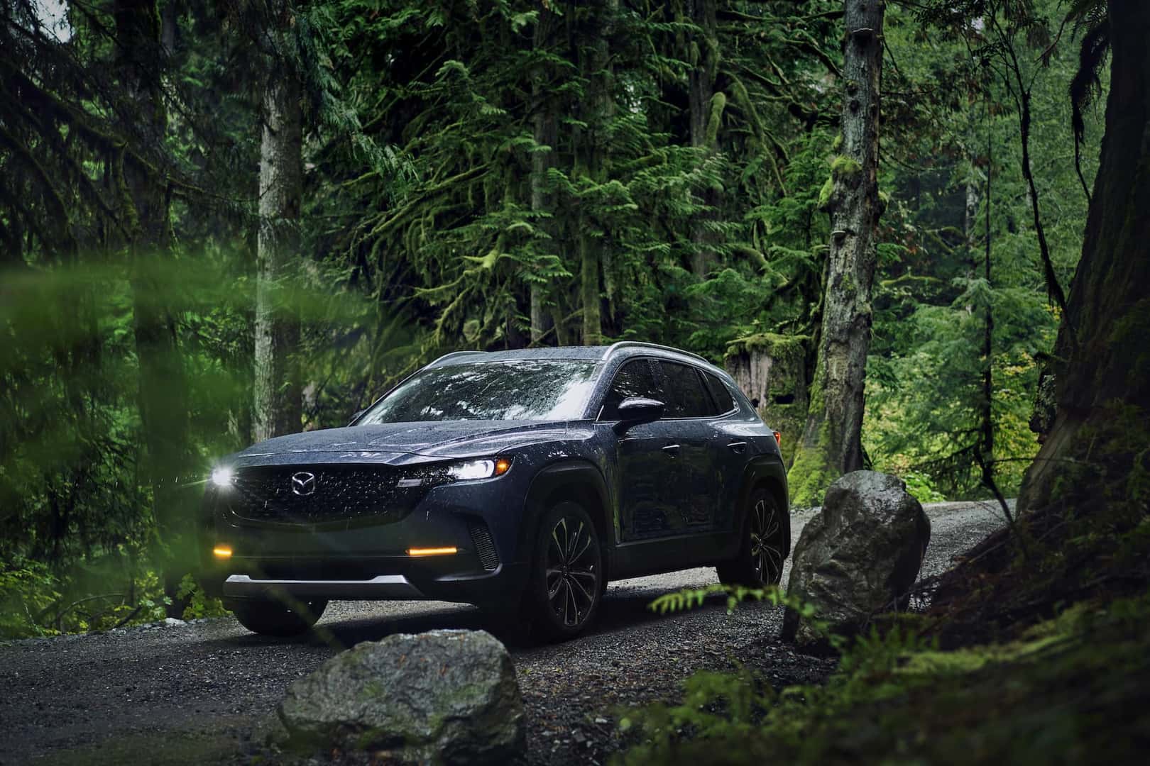 2023 Mazda CX-50 driving amongst green trees