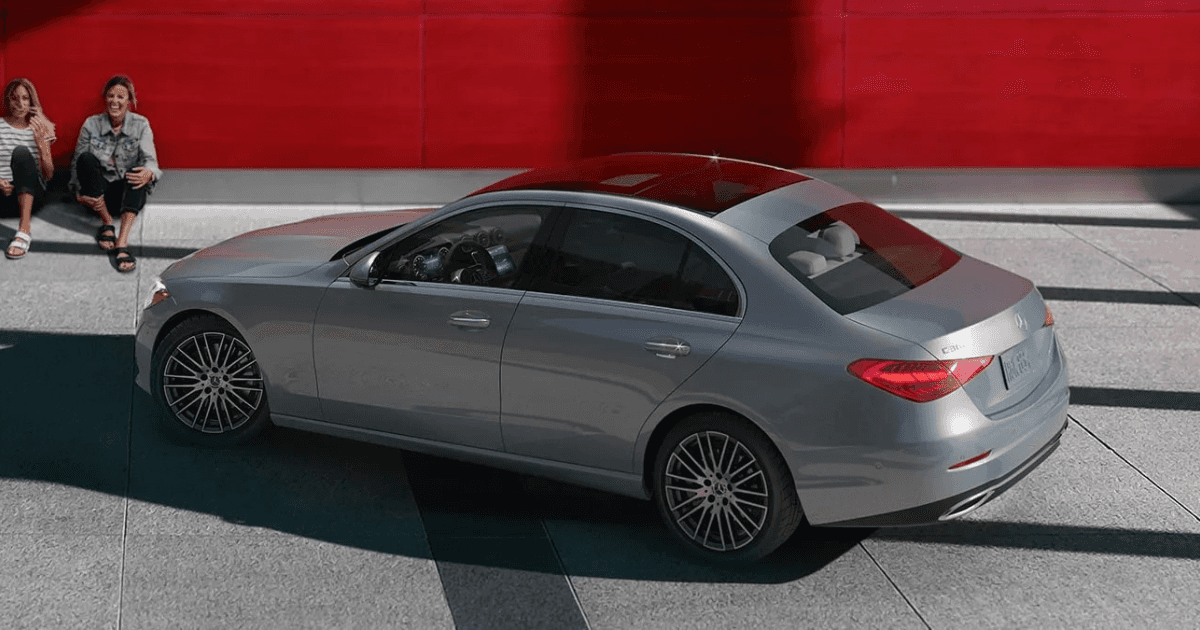 Two women sitting beside a 2025 C-Class sedan