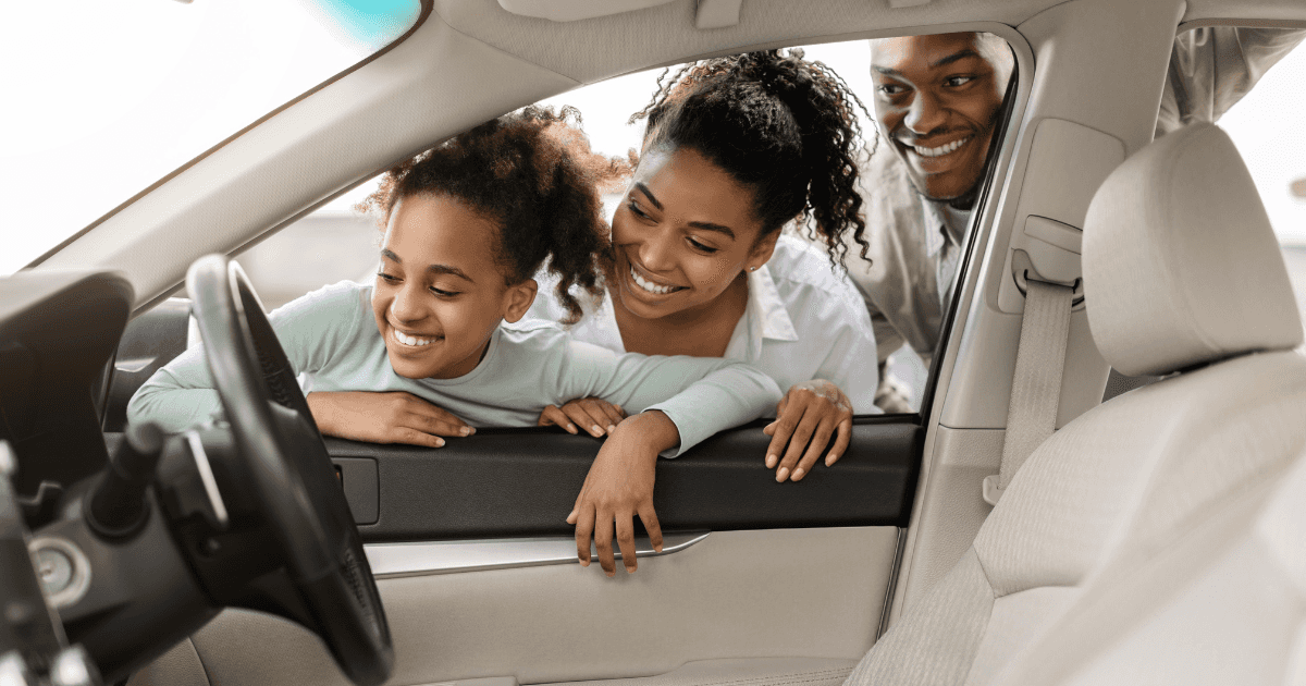 Young cheerful family looking in on their new vehicle