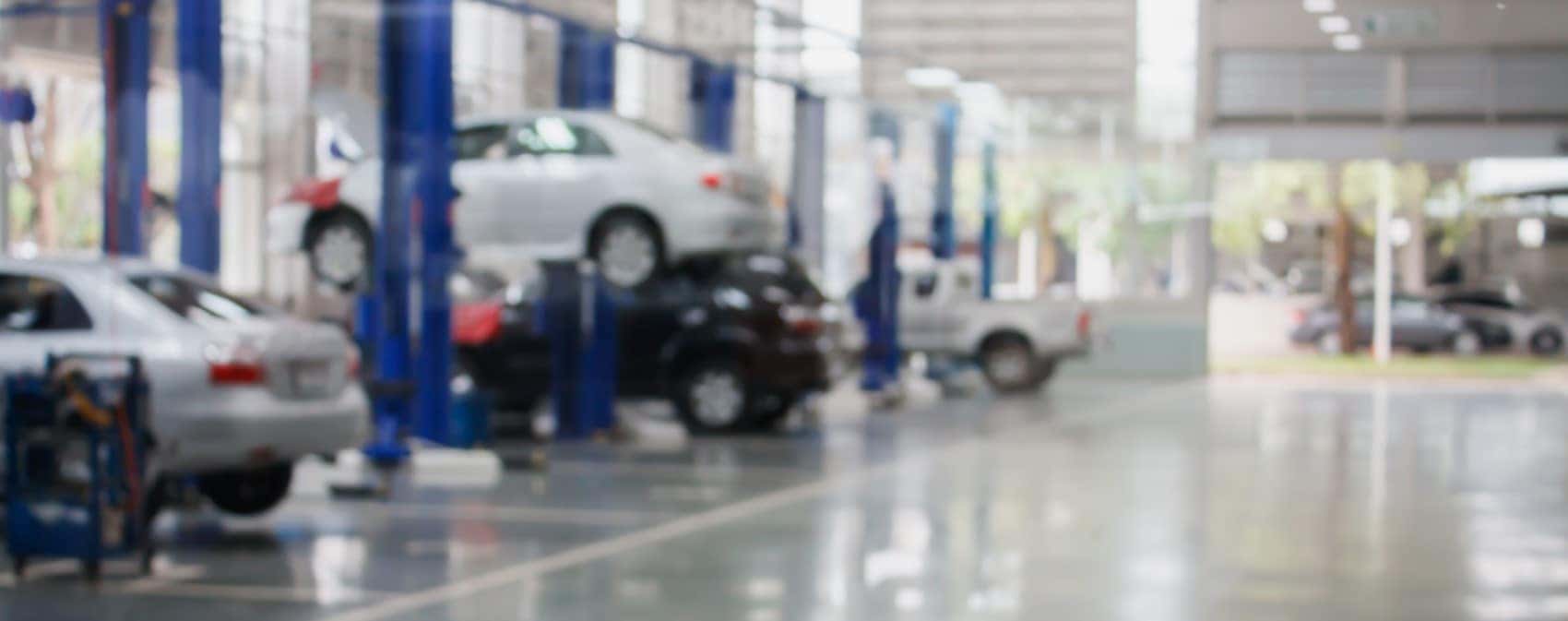 Unfocused shot of car maintenance center cars being serviced up on jacks