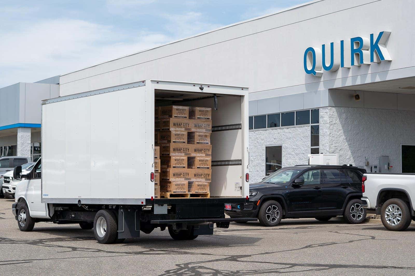 A box truck backed up to the Quirk dealership with pallets of Wrap City chip cases inside