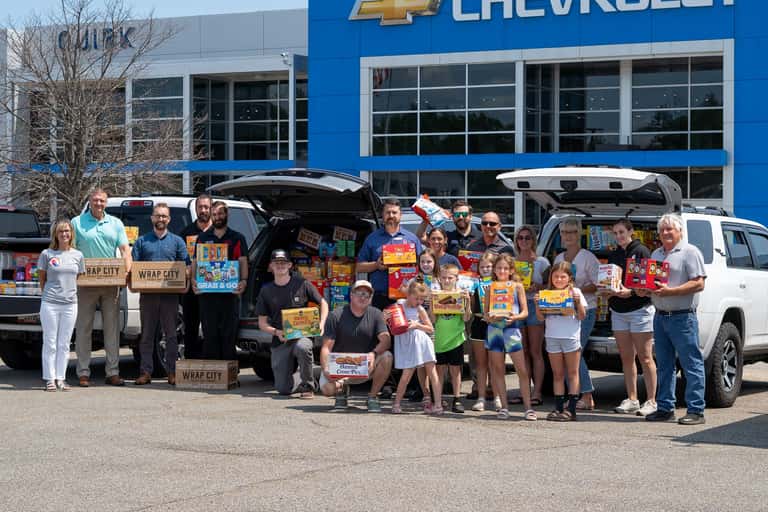 Quirk Auto Group employees and the families of deployed service members gathered with the donated food outside Quirk Chevrolet