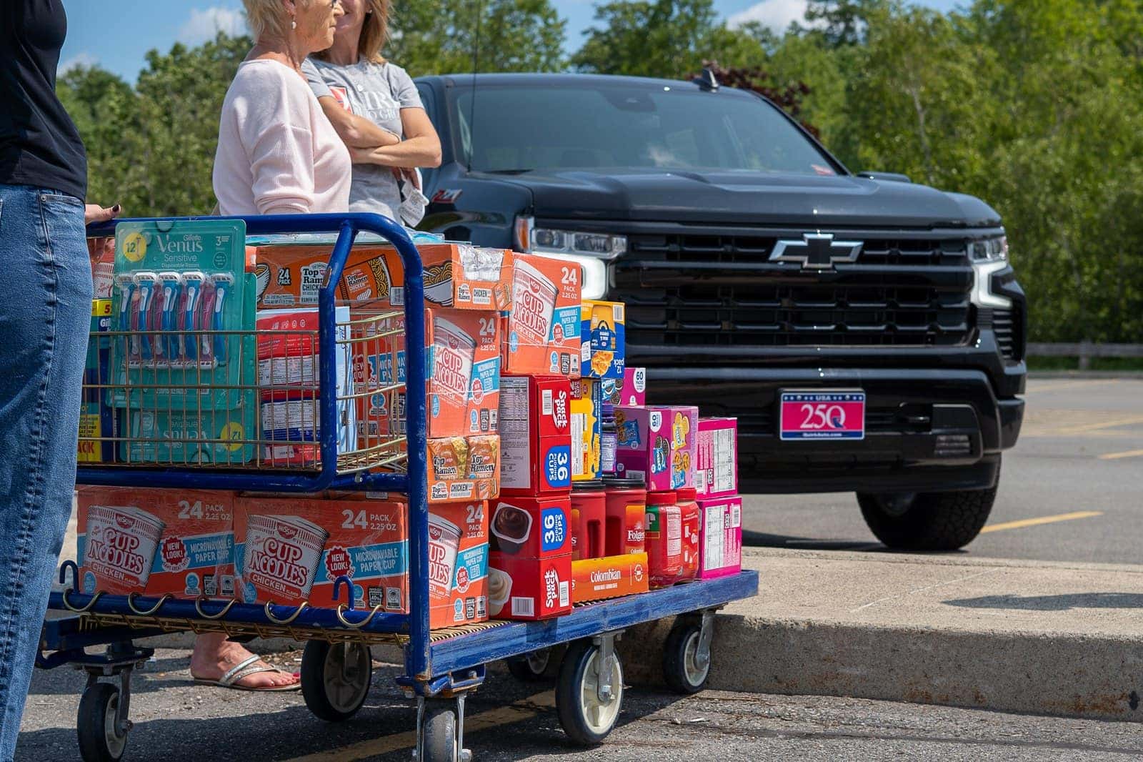 A warehouse cart stacked with Cup Noodles, coffee, snack packs and toiletries bound for the care packages