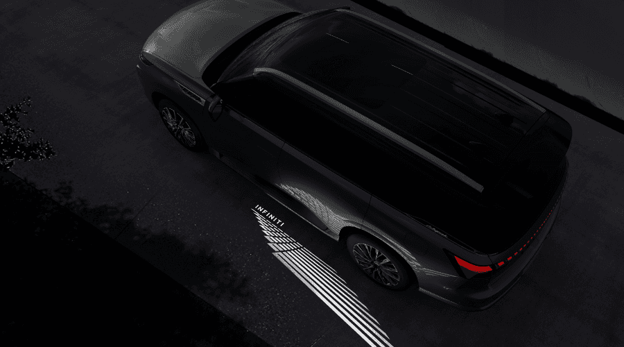 High-angle overhead view of a dark 2026 INFINITI QX80 at night, displaying its premium illuminated welcome light carpet with a glowing geometric pattern and the