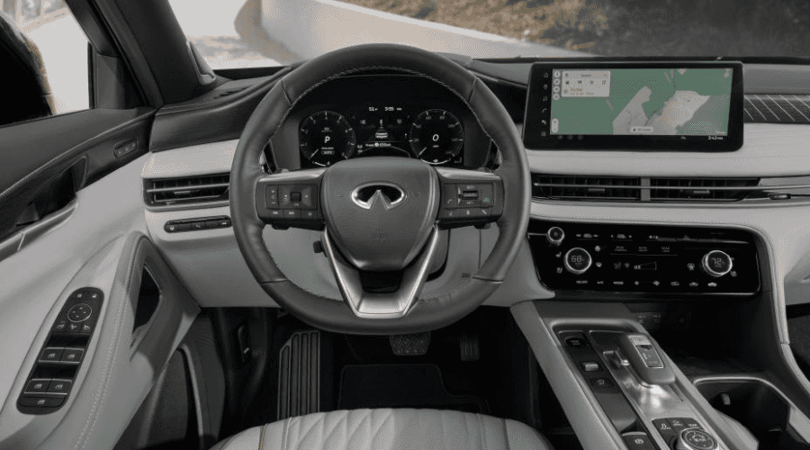 Driver seat POV of the 2026 INFINITI QX60 dashboard showing Google Maps navigation on the central touchscreen display, digital instrument cluster, and leather-wrapped steering wheel at Ramsey INFINITI in Bergen County, NJ