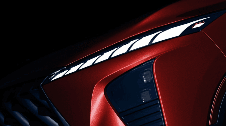 Macro detail of the 2026 INFINITI QX65 digital piano-key LED daytime running lights, dual-element headlight cluster, and dynamic red metallic paint finish available at Ramsey INFINITI in Bergen County, NJ.
