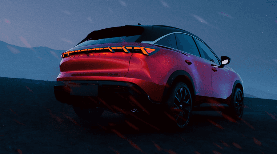 Rear three-quarter view of a red 2026 INFINITI QX65 coupe crossover at dusk, highlighting full-width illuminated piano-key LED taillights, sleek sloping roofline, and rear badge at Ramsey INFINITI in Bergen County, NJ.