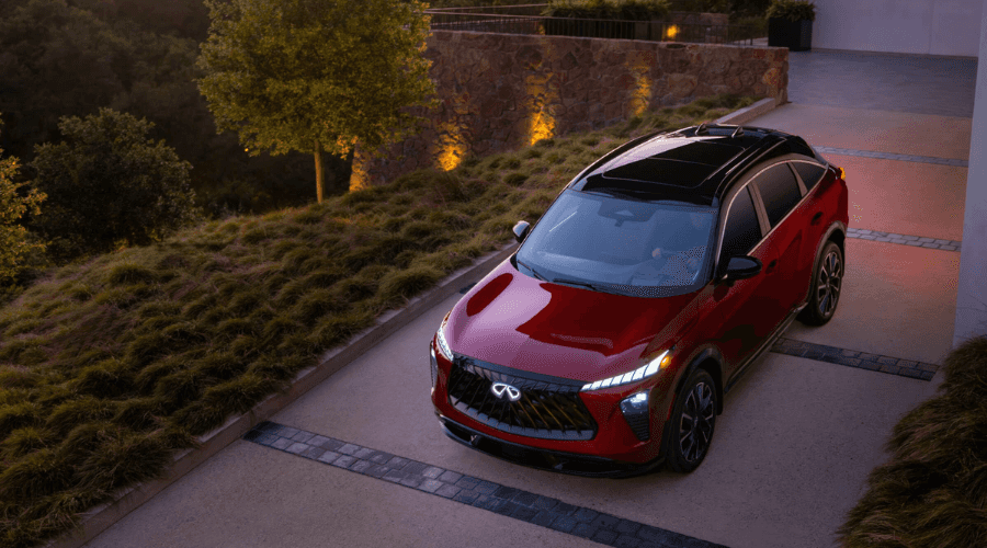 High-angle overhead view of a dynamic red 2026 INFINITI QX65 featuring a black panoramic roof, illuminated LED puddle lighting carpet, and rear taillight bar at Ramsey INFINITI in Bergen County, NJ.