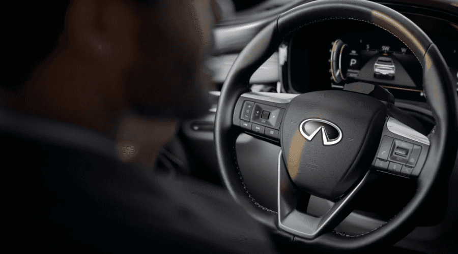 Driver view of the 2026 INFINITI QX60 leather-wrapped steering wheel and digital instrument cluster displaying ProPILOT Assist driver-assist graphics for Bergen County commuters.