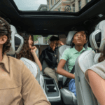 Family enjoying the three-row luxury interior of the 2026 INFINITI QX60 with comfortable leather seating, panoramic moonroof, and second-row captain chairs during a drive through Bergen County, New Jersey.