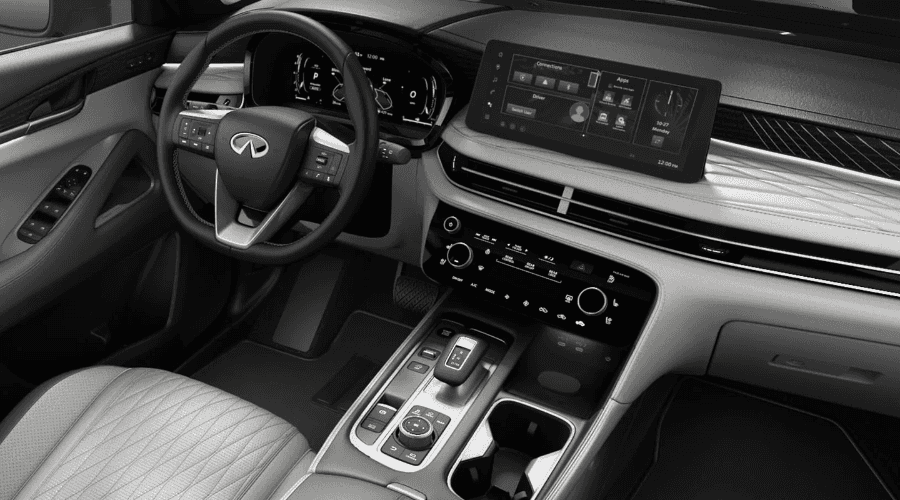 Interior front cabin overview of the 2027 INFINITI QX60 showing light gray quilted leather seating, leather-wrapped steering wheel, high-definition infotainment touchscreen display, climate control panel, and center console, available at Ramsey INFINITI in Mahwah, NJ.