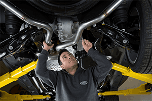 A Land Rover service technician working underneath a Land Rover SUV.