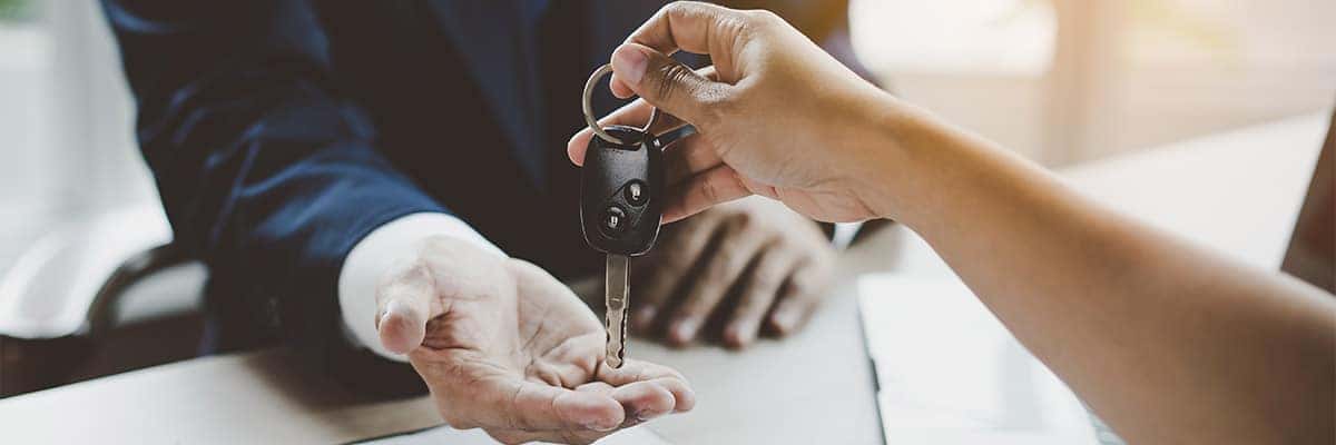 Close up view Hand of customer giving car key to agent after trading in car.
