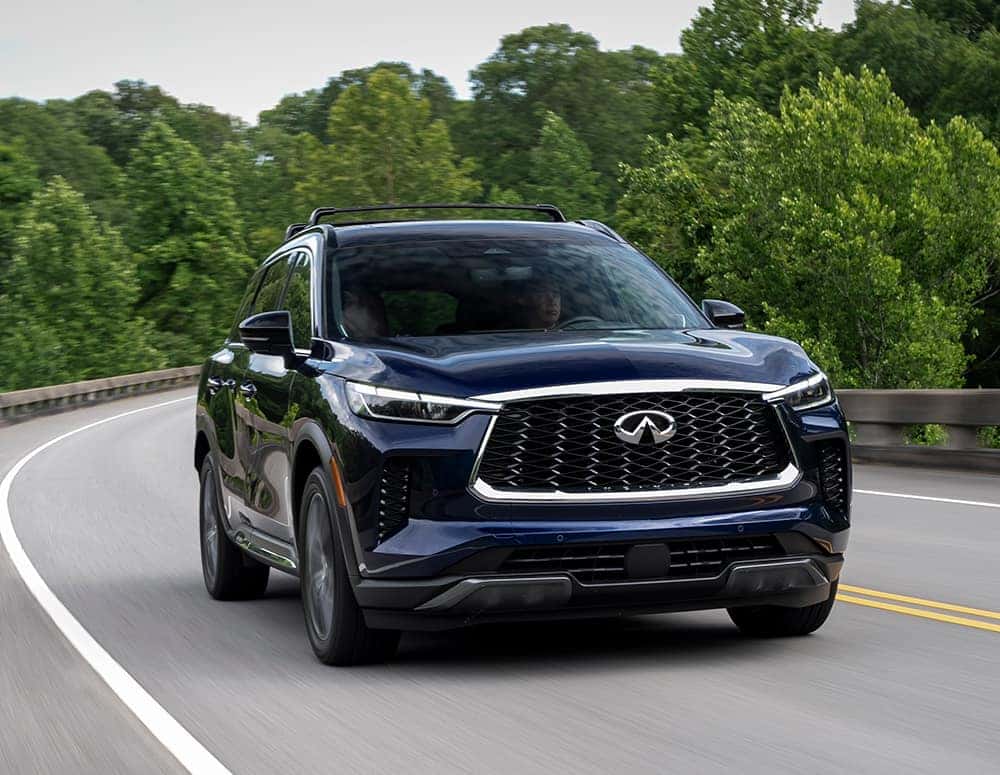 Blue 2024 INFINITI QX60 driving around a corner