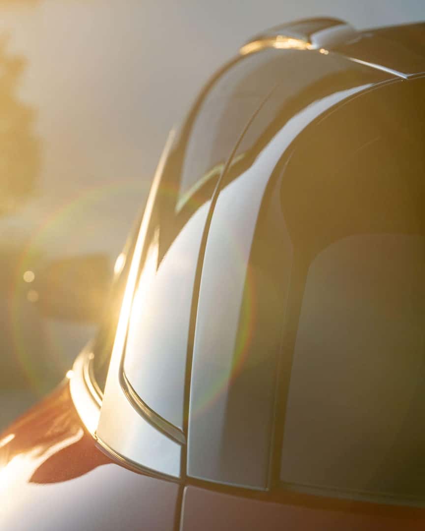 Close-up of the 2027 INFINITI QX65 roofline and black roof trim with sunlight reflecting across the sculpted exterior.