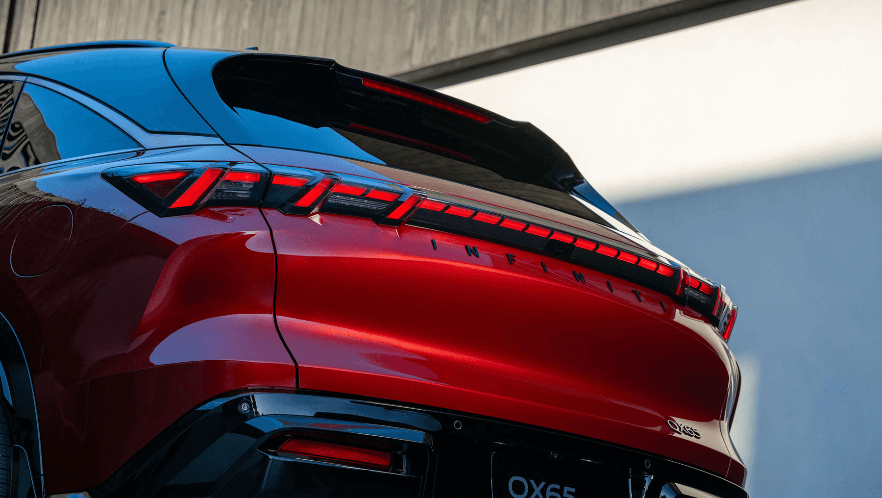 Close-up of the 2027 INFINITI QX65 rear light bar and tailgate with INFINITI lettering and QX65 badging.