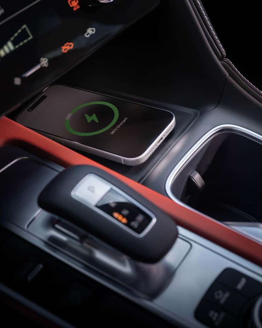 Center console of the 2027 INFINITI QX65 showing wireless smartphone charging pad, shifter, cupholder, and illuminated premium trim.