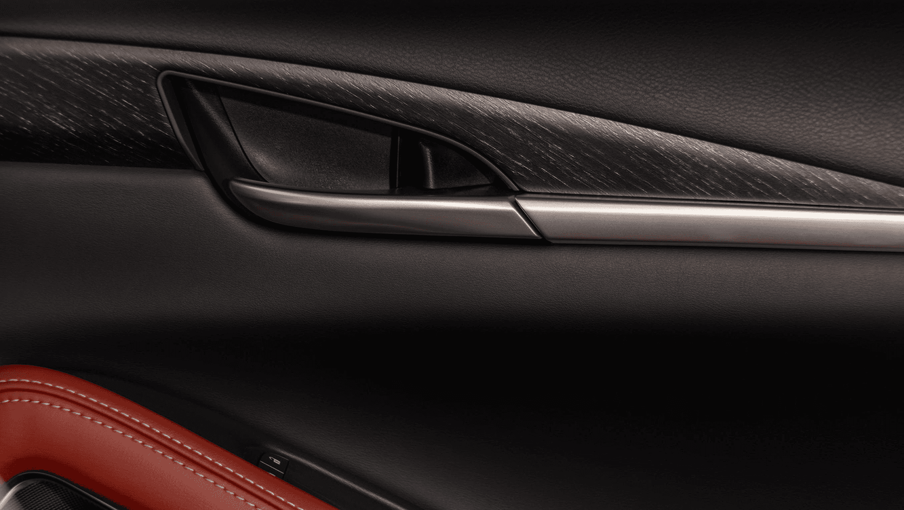 Interior door panel of the 2027 INFINITI QX65 with black soft-touch surfaces, dark wood trim, metallic handle, and red leather accent.
