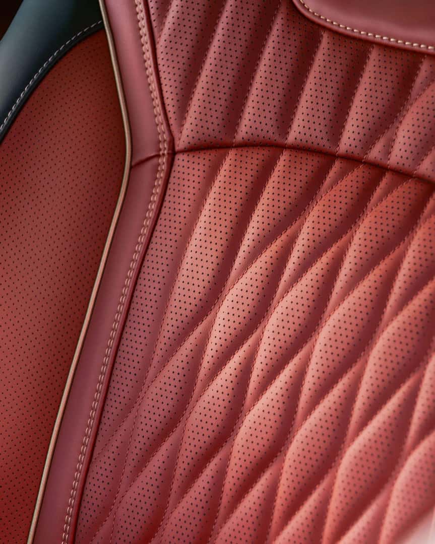 Close-up of the 2027 INFINITI QX65 front seat upholstery in red quilted perforated leather with contrast stitching and sculpted bolsters.