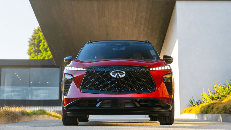Front view of the 2027 INFINITI QX65 in red, highlighting the bold grille, LED daytime running lights, and wide athletic stance.