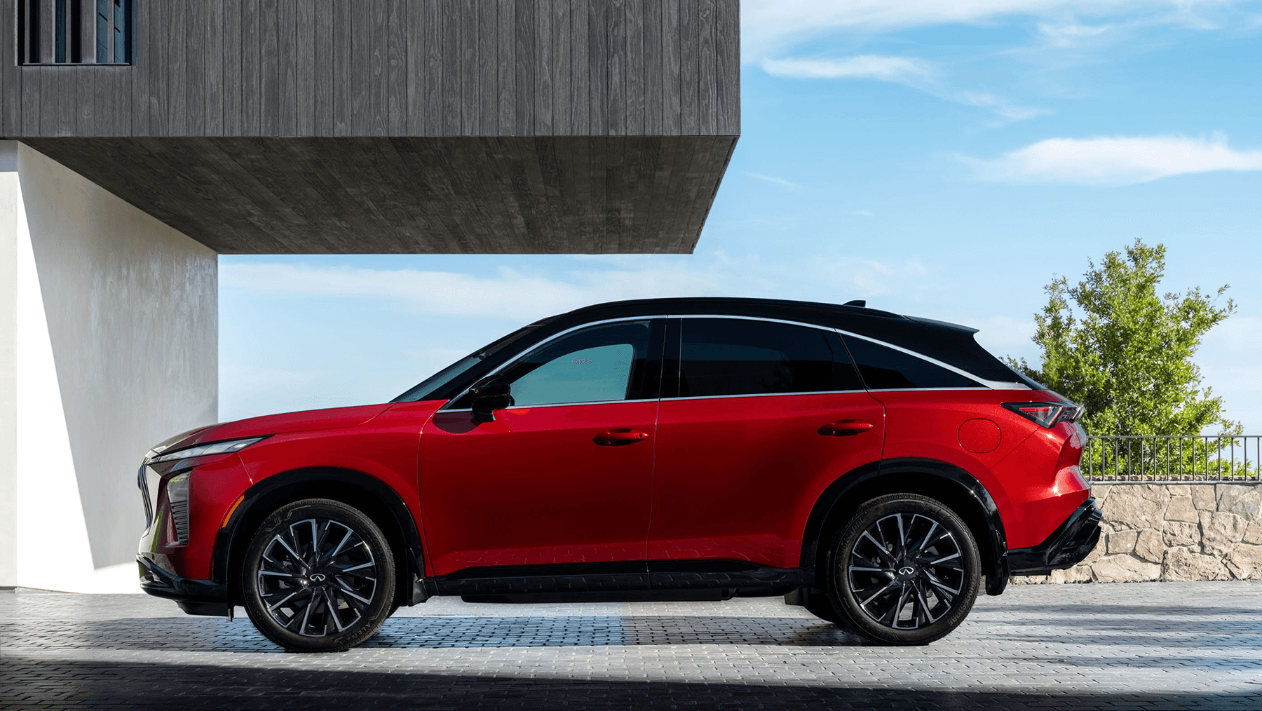Full side profile of the 2027 INFINITI QX65, emphasizing the sleek coupe-like silhouette, black roof, and large alloy wheels.