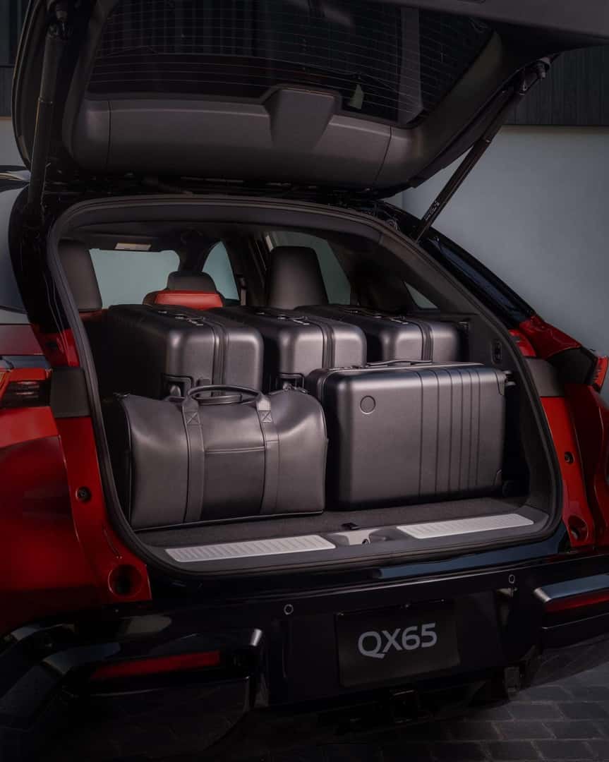 Open cargo area of the 2027 INFINITI QX65 filled with black luggage, showing rear storage capacity and premium interior trim.