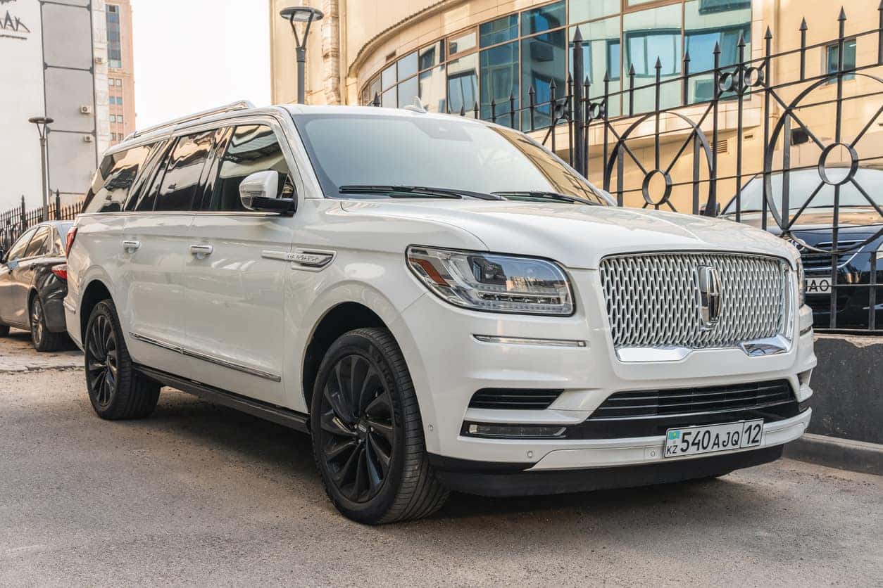 A white Lincoln Navigator is parked near the fence